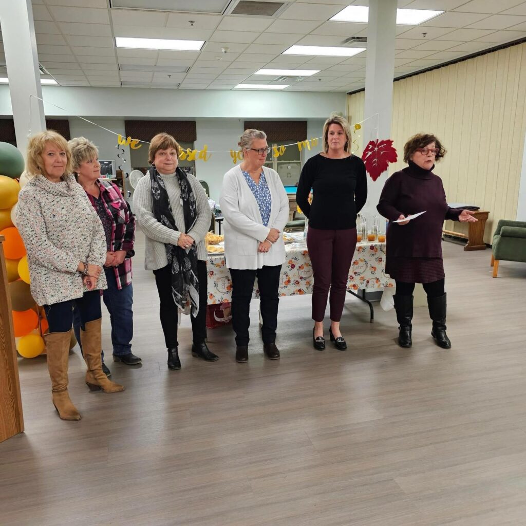 group of women standing holding a check