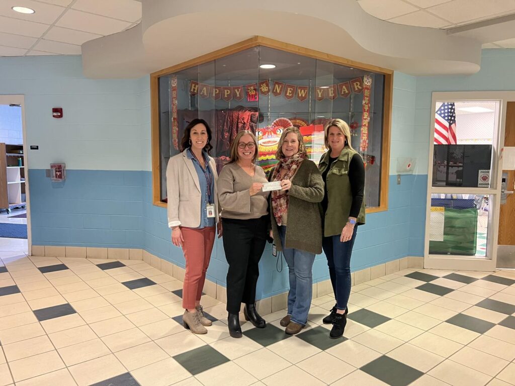 group of women standing holding a check