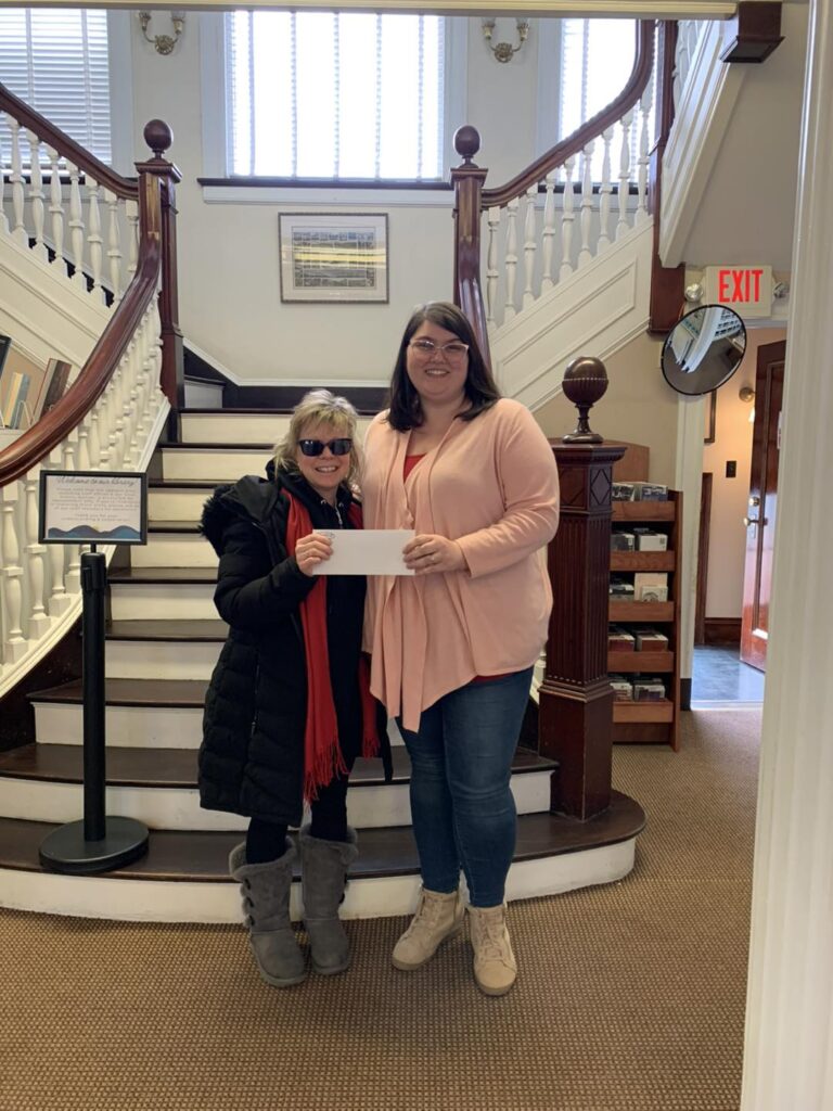 Two women standing holding a check