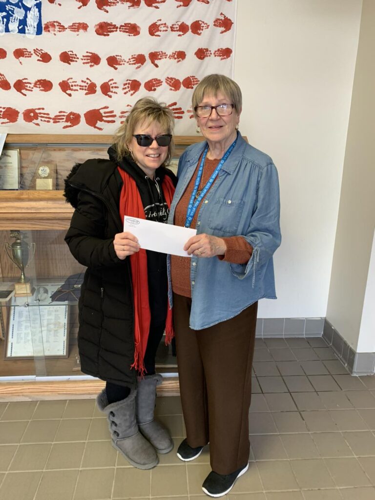 Two women standing holding a check