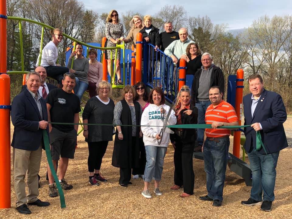 Group of people cutting ribbon at playground